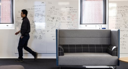 A person walking past a wall filled with number AI solus