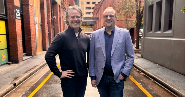 Two men smile at the camera