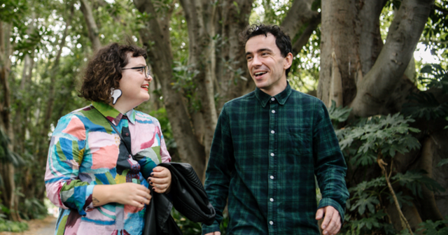 Two people walk in a garden.